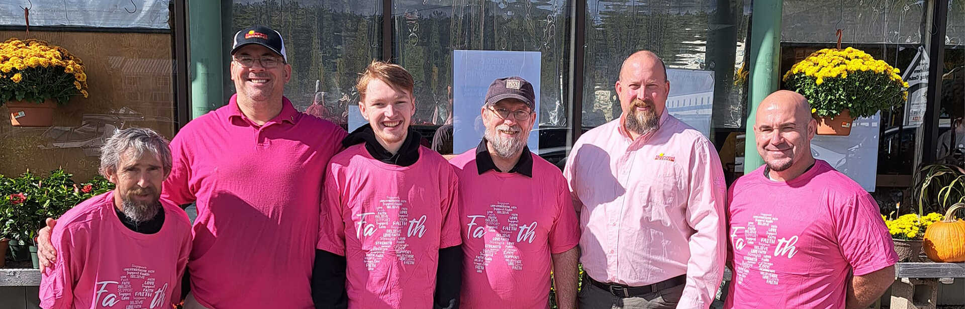 AGNE team members standing together in pink shirts.